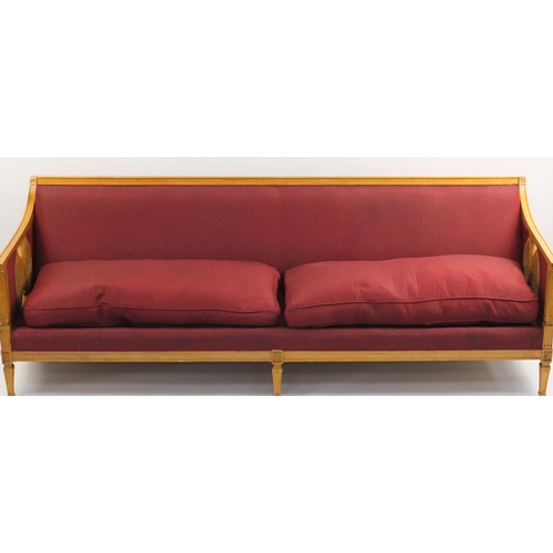 39 - Light wood settee with cane panelled ends, plum upholstery and cushions, 223cm wide