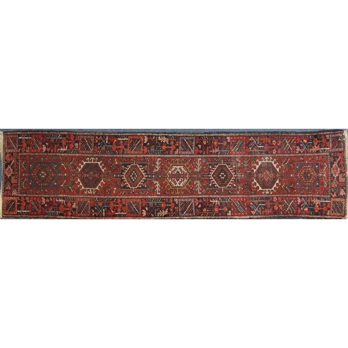 125 - Rectangular Persian Heriz carpet runner, the central field having a stylised repeat flower head desi... 