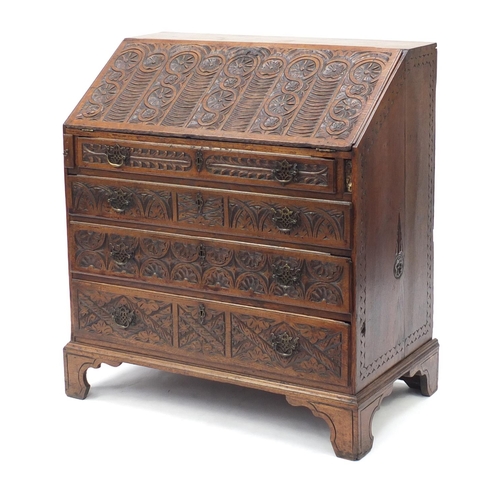 6 - Oak bureau profusely carved with floral motifs, the fall enclosing a fitted interior above four grad... 