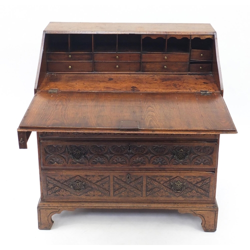 6 - Oak bureau profusely carved with floral motifs, the fall enclosing a fitted interior above four grad... 