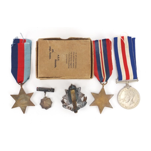 662 - Three British Military World War II medals, and East Surrey cap badge and silver and enamel Royal Ar... 