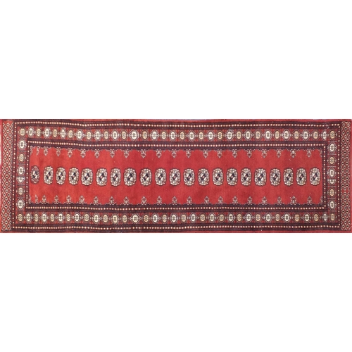 26 - Bokara red ground carpet runner with blue and cream motifs, 237cm x 79cm
