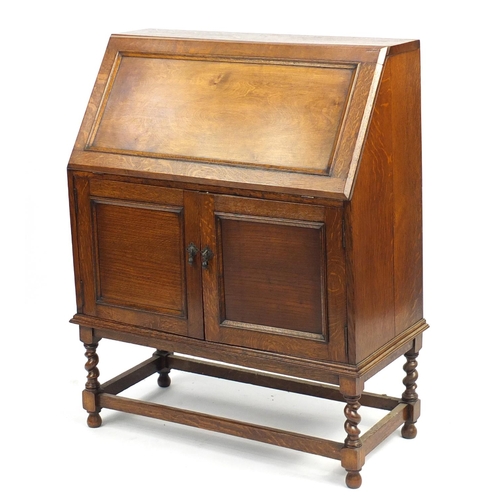 102 - Oak bureau, the fall enclosing a fitted interior above a pair of cupboard doors and barley twist leg... 