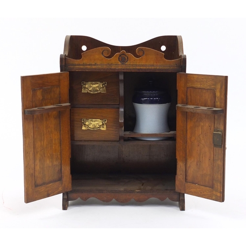 61 - Arts & Crafts carved oak two door smokers cabinet with tobacco jar, 46cm high