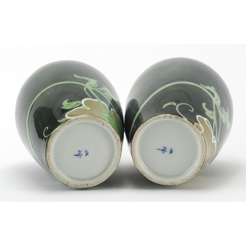 492 - Pair of Japanese porcelain vases, hand painted with flowers onto a green ground, 21cm high