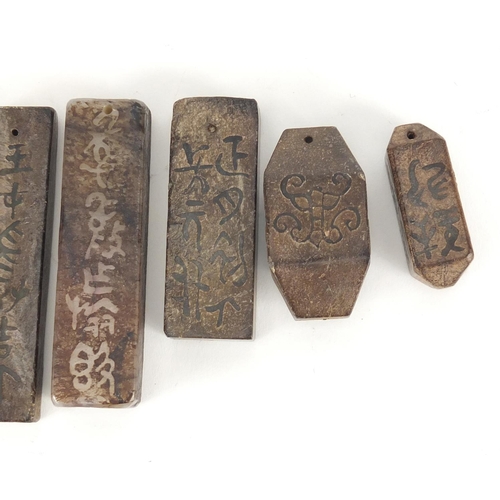 379 - Six Chinese stone pendants carved with calligraphy, the largest 8.5cm in length