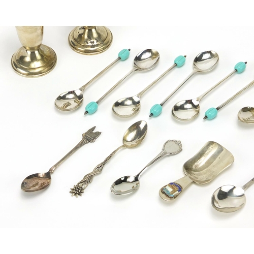 2364 - Silver and white metal cutlery including a pair of sterling casters, a sterling caddy spoon and souv... 