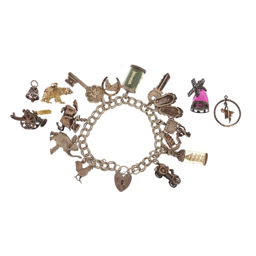 2462 - Silver charm bracelet with a selection of mostly silver charms including emergency one pound note, S... 
