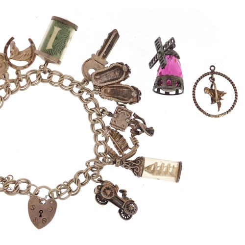 2462 - Silver charm bracelet with a selection of mostly silver charms including emergency one pound note, S... 