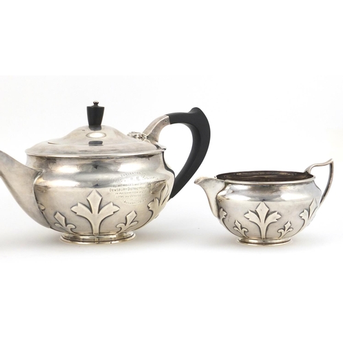 520 - Arts & Crafts style silver three piece tea service embossed with stylised motifs, the teapot with eb... 