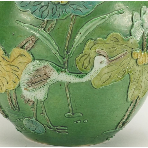 224 - Chinese porcelain green glazed jar, decorated in relief with a craned amongst flowers and reeds, 15.... 