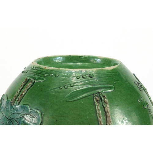 224 - Chinese porcelain green glazed jar, decorated in relief with a craned amongst flowers and reeds, 15.... 