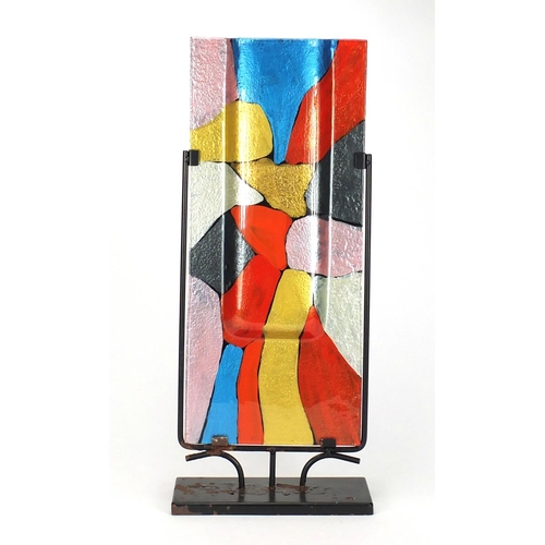 2325 - Modernist painted glass sculptural vase housed in a metal stand, overall 61cm high