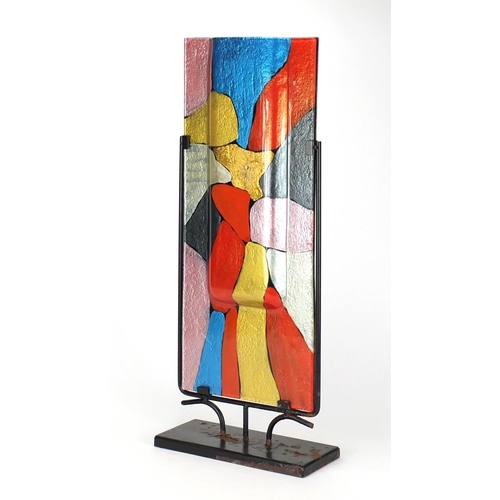 2325 - Modernist painted glass sculptural vase housed in a metal stand, overall 61cm high