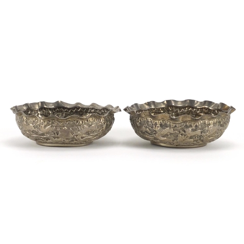 375 - Pair of Indian unmarked silver bowls, each embossed with lions chasing antelope, each 12cm wide, app... 