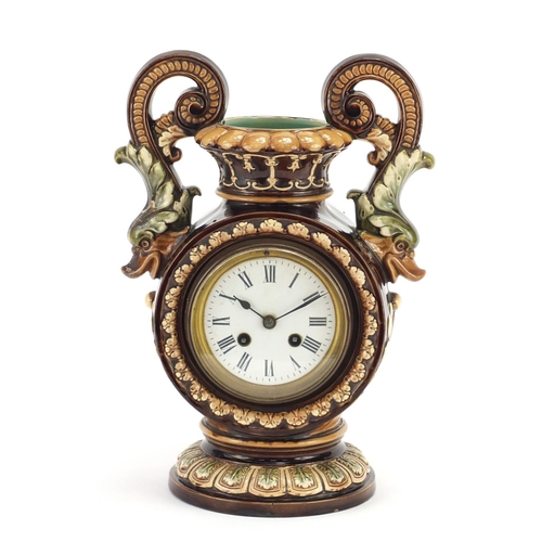 715 - Continental pottery mantel clock in the form of vase with twin dolphin handles, the enamelled dial w... 