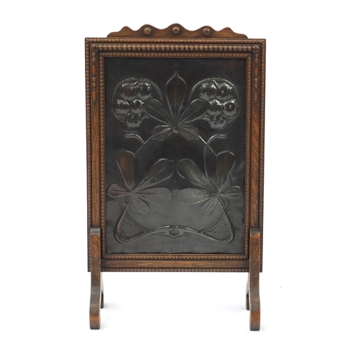 2129 - Arts & Crafts oak fire screen, the coppered panel with stylised flowers, 75cm high
