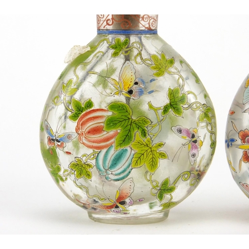 669 - Two Chinese glass snuff bottles with stoppers, each enamelled with butterflies, character marks to t... 
