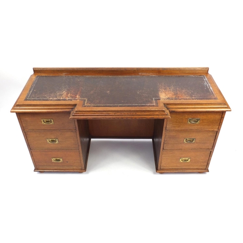44 - Oak twin pedestal desk, the breakfront top with tooled leather insert, the six drawers with inset br... 