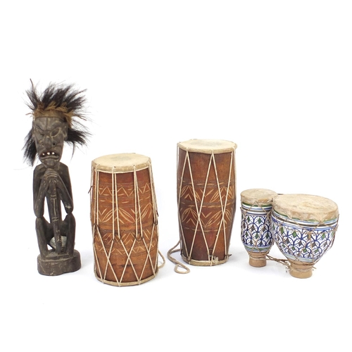 503 - Three African animal skin drums and a carved wood figure, the largest 53cm high