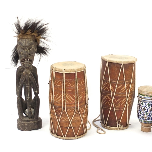 503 - Three African animal skin drums and a carved wood figure, the largest 53cm high