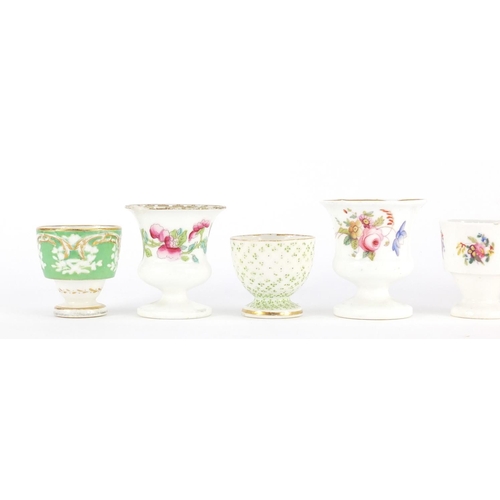 612 - Seven early 18th century egg cups, predominantly Coalport, some hand painted with flowers, each with... 