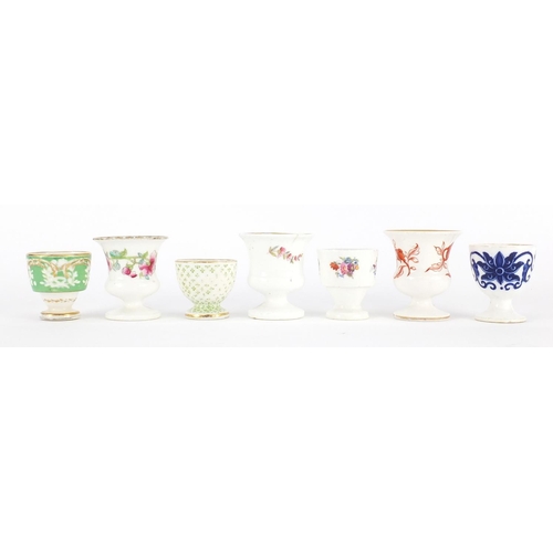 612 - Seven early 18th century egg cups, predominantly Coalport, some hand painted with flowers, each with... 