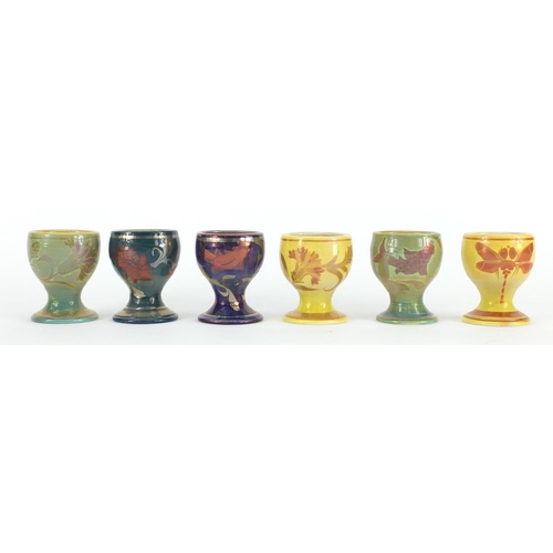 689A - Set of six Johnathon Chiswell Jones lustre egg cups, hand painted with stylised fish, flowers and in... 