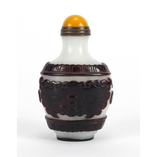 747 - Chinese Peking cameo glass snuff bottle with stopper, decorated with mythical heads, 8cm high