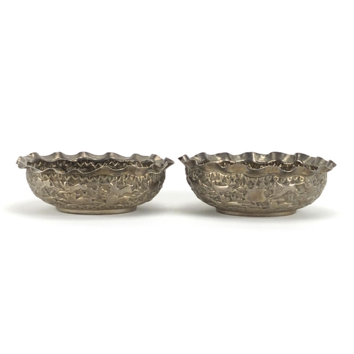 683 - Pair of Indian unmarked silver bowls, each embossed with lions chasing antelope, each 12cm wide, app... 