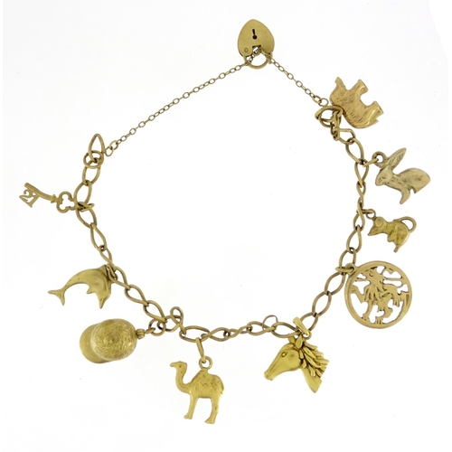 2713 - 9ct gold charm bracelet with mostly 9ct gold charms including jockey cap, camel, dolphin and horse, ... 