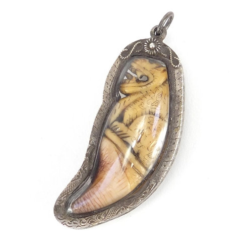 108 - Ivory tooth carved with a mythical animal, encased in a silver coloured metal pendant mount, overall... 