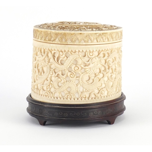 480 - Chinese Canton ivory pot and cover, finely carved with dragons amongst clouds, raised on a carved ha... 