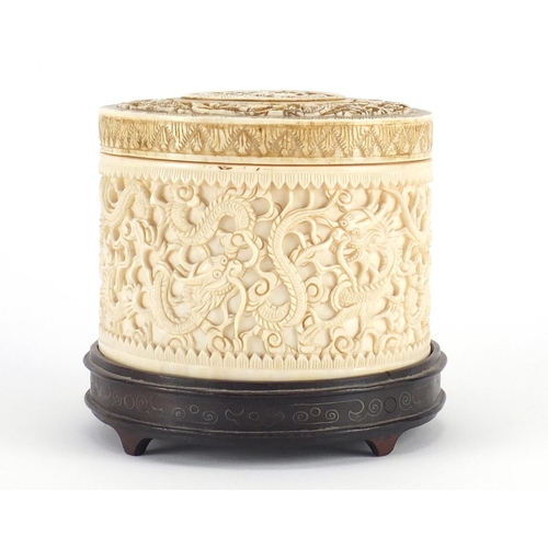 480 - Chinese Canton ivory pot and cover, finely carved with dragons amongst clouds, raised on a carved ha... 