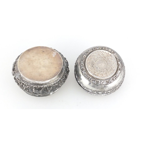 515 - Two Middle Eastern unmarked silver coloured metal circular boxes (both test as silver), embossed wit... 