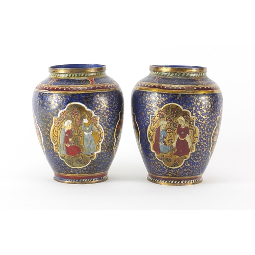 567 - Pair of Islamic metal vases, hand painted with calligraphy and panels of figures and flowers, each 1... 