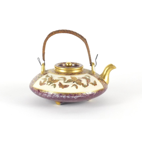 453 - Japanese Satsuma pottery squatted teapot with swing handle, hand painted and gilded with panels of b... 