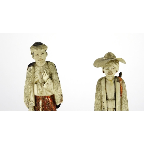 545 - Pair of Indian carved ivory figures raised on circular wood stands, the largest 16cm high