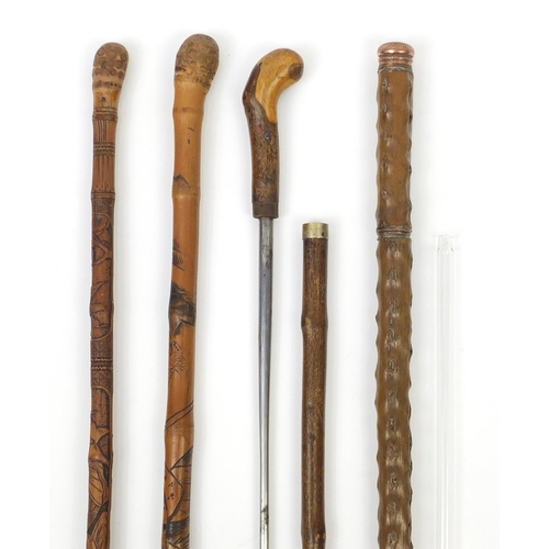 88 - Four walking sticks comprising two Chinese carved bamboo examples, a sword type stick and one other ... 