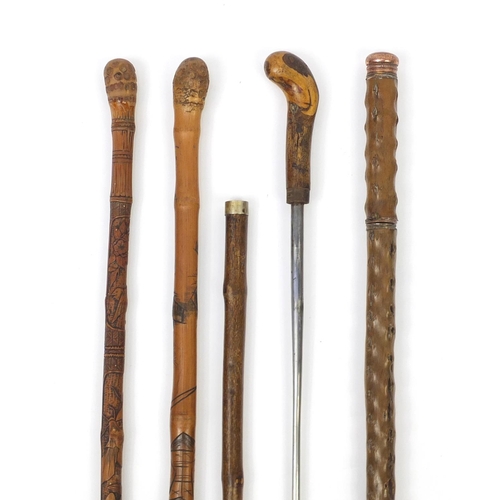 88 - Four walking sticks comprising two Chinese carved bamboo examples, a sword type stick and one other ... 