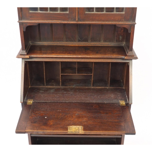 12 - Arts & Crafts oak bureau bookcase with a pair of leaded glass doors above a fall, frieze drawer and ... 