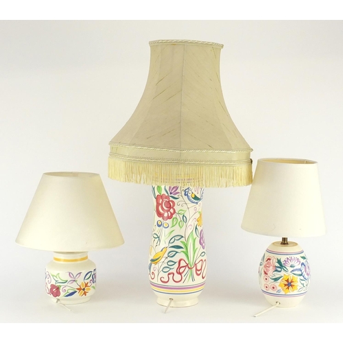 2201 - Three Poole pottery lamp bases with shades, each hand painted with flowers, the largest overall 62cm... 