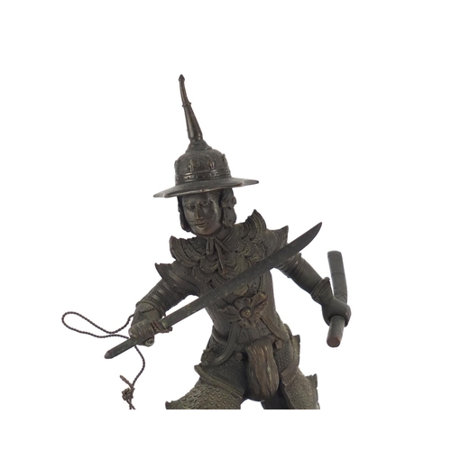 2343 - Thai patinated bronze warrior raised on circular ebonised stand, 23cm high