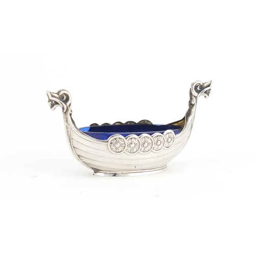 2598 - Unmarked silver Viking longboat salt with blue glass liner, embossed Norge, 8.5cm wide