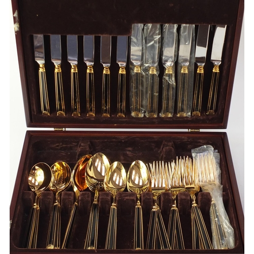 2311 - Two canteens of stainless steel cutlery, with gilt and black enamel handles, the largest canteen 39.... 