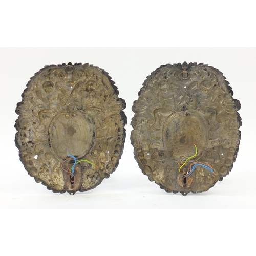 2110 - Pair of silver plated two branch wall sconces, embossed with putti and leaves, each 38cm high