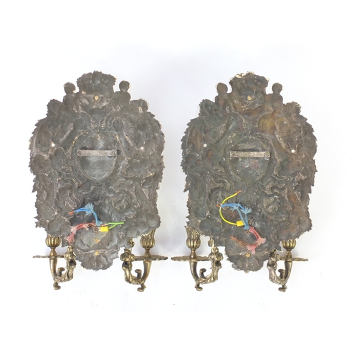2111 - Pair of silver plated two branch wall sconces, decorated with putti and swags, each 36cm high