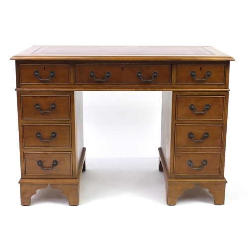 2 - Yew twin pedestal desk with tooled red leather insert, above a series of eight drawers, 67cm H x 107... 