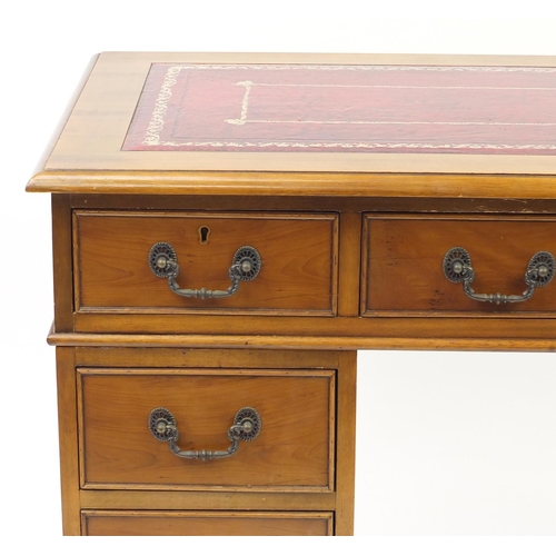 2 - Yew twin pedestal desk with tooled red leather insert, above a series of eight drawers, 67cm H x 107... 