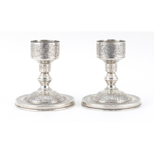 887 - Pair of Persian silver candlesticks with engraved decoration, impressed marks to the base, 11cm high... 